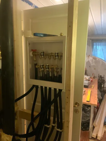 Fordelerskap i ny vegg, med sorte varerør ned i stenderverket